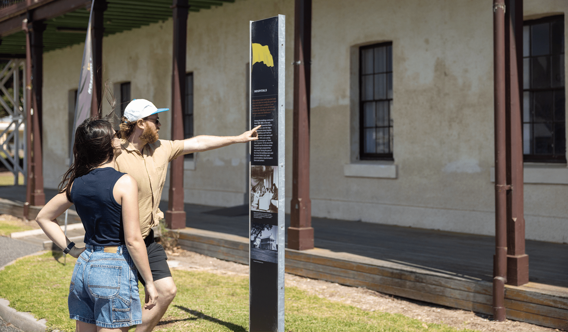 A man pointing at an interpretive sign with a woman reading off the board.